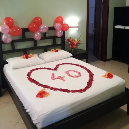 Red rose petal heart bed decoration with a fresh flower vase