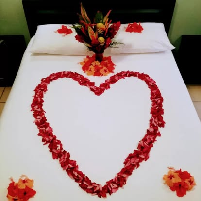 Heart-shaped rose petal bed decoration with red balloons