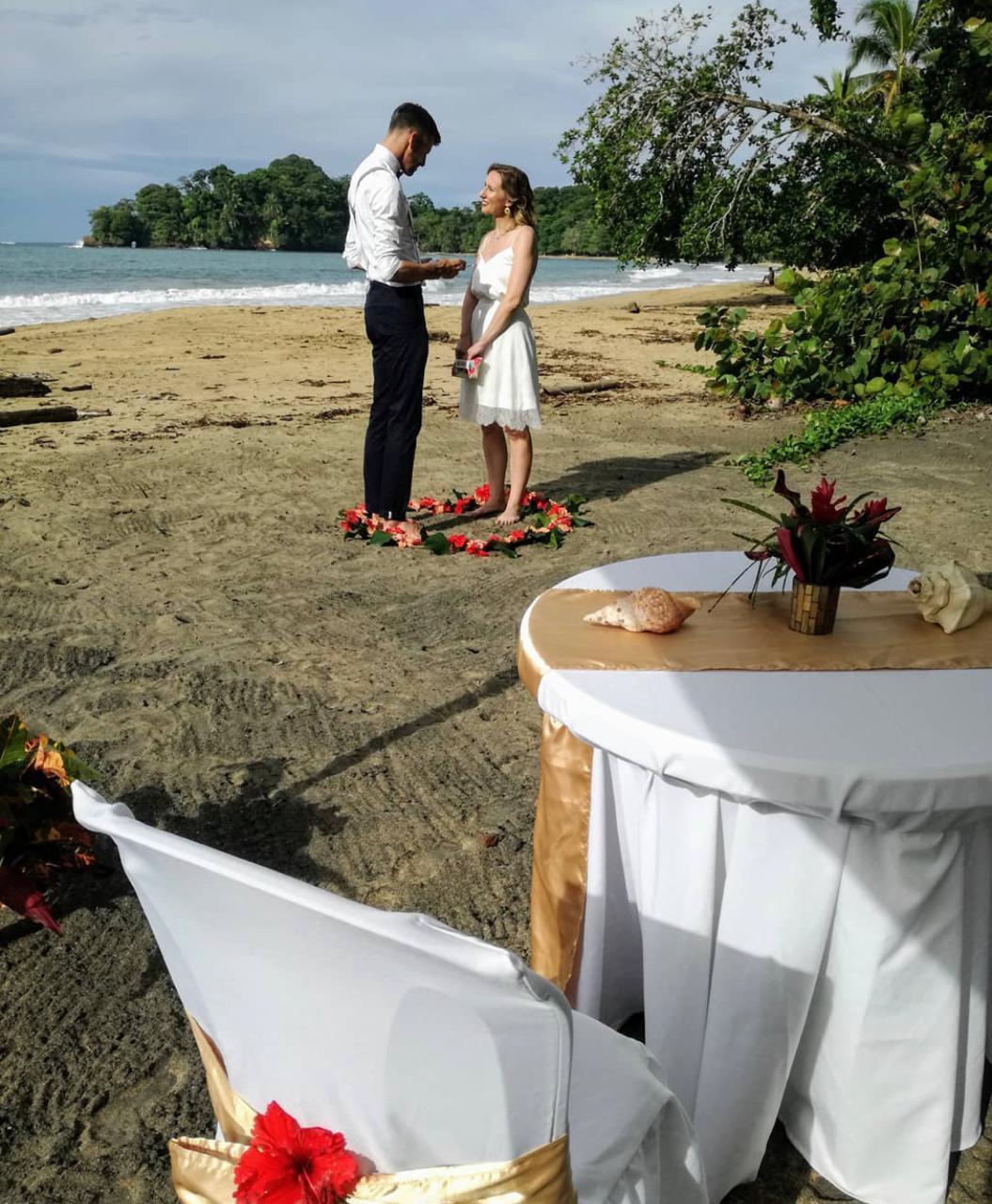 Couple exchanging vows barefoot on the beach inside a flower heart