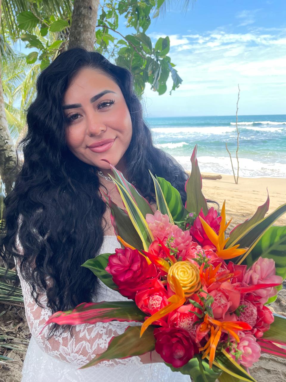 Bride holding a tropical heliconia and ginger bouquet on the beach