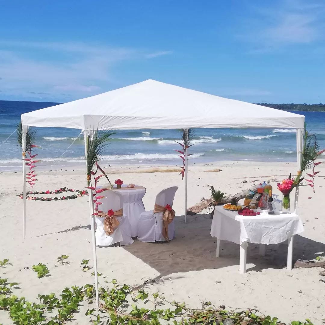 Beach wedding setup with white chairs and tropical flowers facing the Caribbean sea