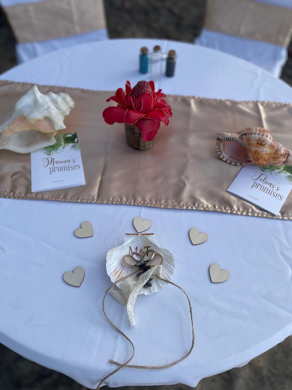 Wedding ring shell and vow cards on a gold table runner